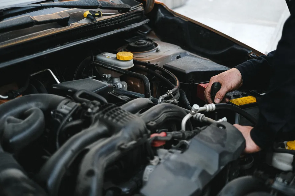 Mechanic's hands working on a car engine under the open hood